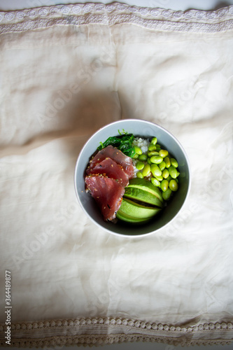 poke bowl fresh tuna soybeans and avocado on white linen copy space