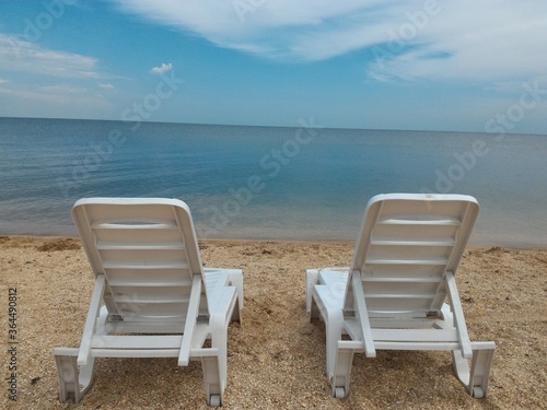 beach chairs on the beach front of transparent blue sea