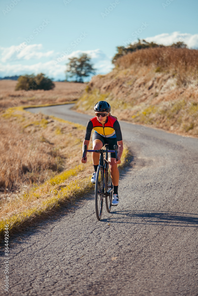 Young woman cycles her road bike on a beautiful countryside road