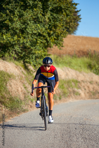Elite athlete trains cycling with his road bike on a sunny day among wheat fields