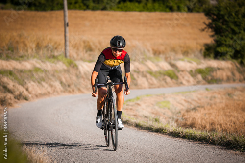Elite athlete trains cycling with his road bike on a sunny day among wheat fields
