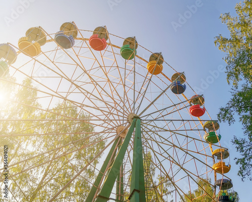 Multi-colored Ferris wheel in the park in a sunny summer day. Bottom view.