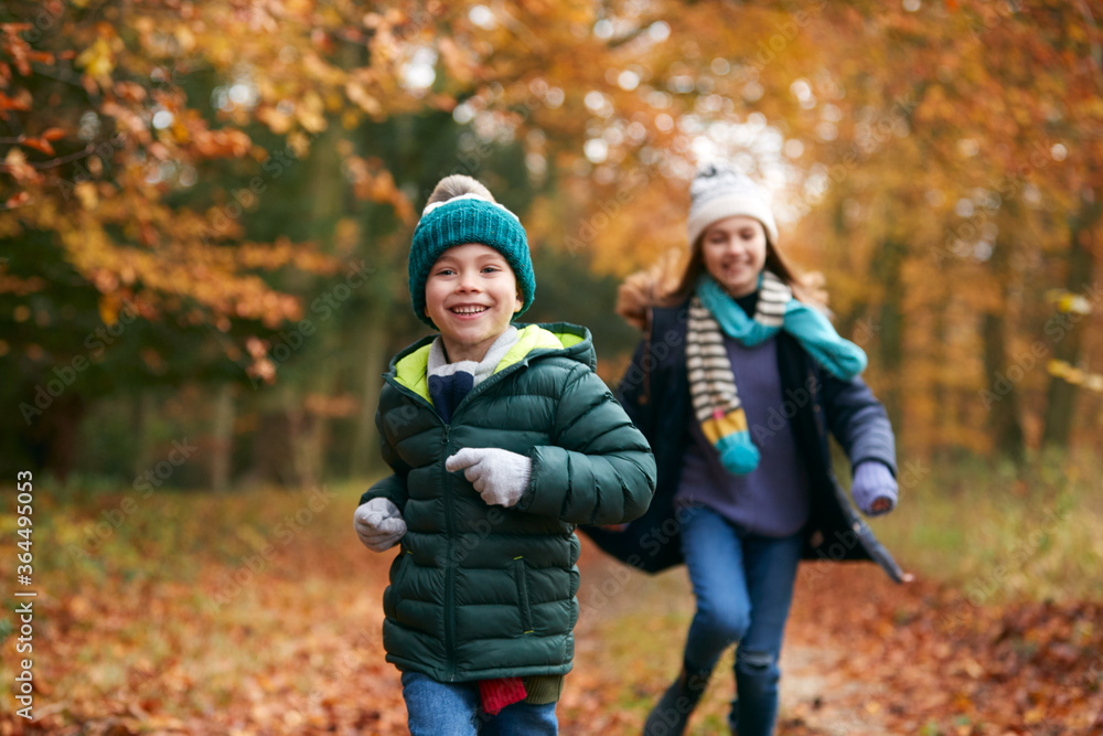 Two Smiling Children Having Fun Running Along Path Through Autumn Woodland Together Two Smiling Children Having Fun Running Along Path Through Autumn Woodland Together