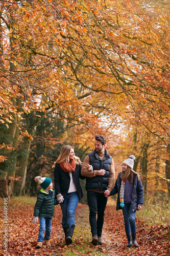 Family Walking Arm In Arm Along Autumn Woodland Path Together