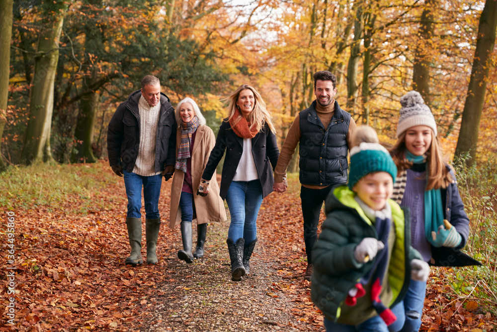 Multi-Generation Family Enjoying Walk Along Autumn Woodland Path Together Multi-Generation Family Enjoying Walk Along Autumn Woodland Path Together
