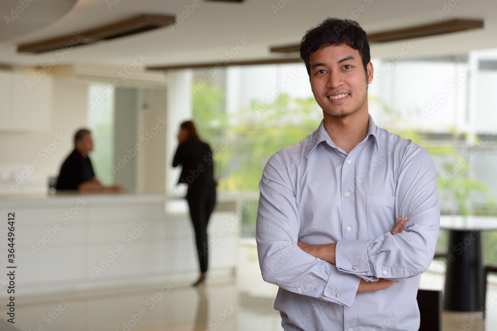 Happy young Asian businessman smiling with arms crossed in the office building Happy young Asian businessman smiling with arms crossed in the office building