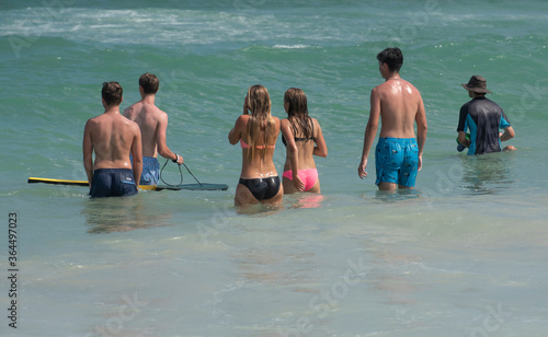 A group of teenagers wait for breaking waves at the beach. photo