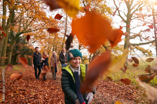 Children Throwing Leaves As Multi-Generation Family Walk Along Autumn Woodland Path photo