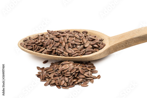 Close up of linseed or flax seeds on a wooden spoon with a pile next to it seen from the side and isolated on white background