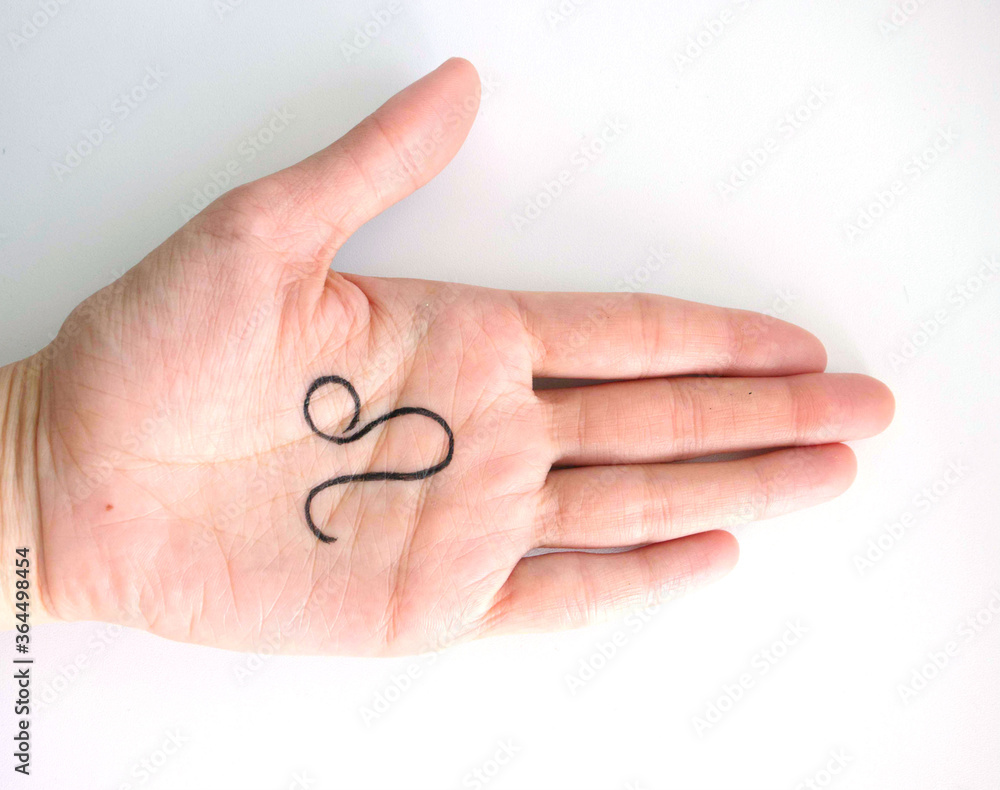 The palm of a young girl, top view, with a black felt-tip pen painted the zodiac sign Leo, on a light background. Features, characteristics of the sign Leo in the palm of your hand, lines of fate, The palm of a young girl, top view, with a black felt-tip pen painted the zodiac sign Leo, on a light background. Features, characteristics of the sign Leo in the palm of your hand, lines of fate,