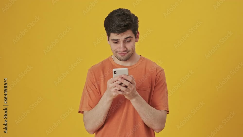 Bearded handsome man wearing in t-shirt using smartphone over yellow background