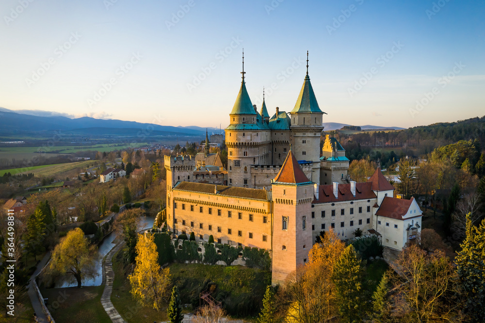 Side view of Bojnice castle with one wall bathed in lovely morning light. Medieval heritage site with towers illuminated by golden light in the morning, Slovakia, Europe.