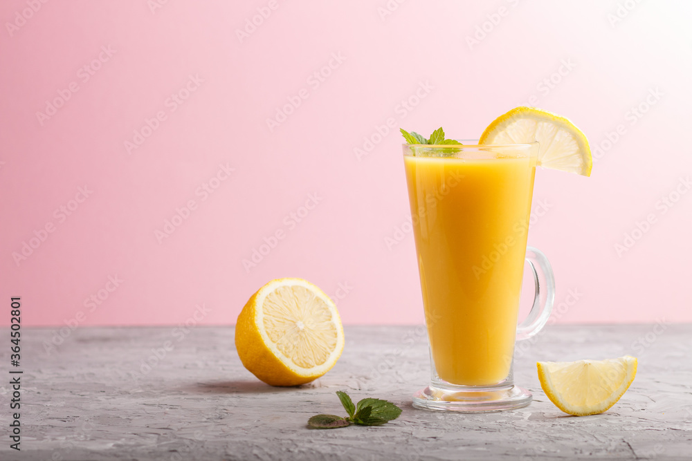 Fototapeta premium Glass of lemon drink on a gray and pink background. Side view