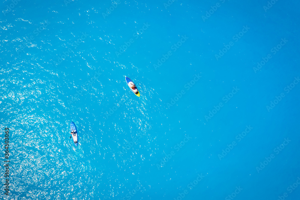Luftaufnahme eines Pärchens auf Stand Up Paddle Brettern über türkisem Meer Luftaufnahme eines Pärchens auf Stand Up Paddle Brettern über türkisem Meer