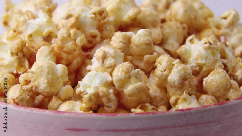 Rotating of popcorn with caramel in ceramic bowl on white background. Side view, close up, macro. Rotating of popcorn with caramel in ceramic bowl on white background. Side view, close up, macro.