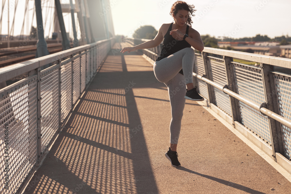 Obraz premium Young woman exercising at the bridge 