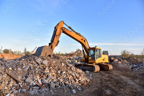 Excavator work at landfill with concrete demolition waste. Salvaging and recycling building and construction materials. Industrial waste treatment plant. Reuse concrete for new construction