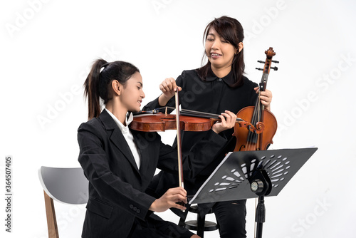 In violin practice class,two beautiful asian woman hold wooden violin.teach and practice playing violin together to prepare for the concert.