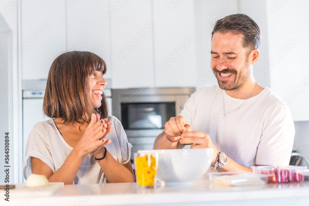 A Caucasian couple cooking together at home, cooking in confinement, cooking with the family. Coronavirus, covid-19. Cooking two lovers in the kitchen at home