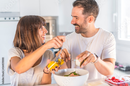 A Caucasian couple cooking together at home  cooking in confinement  cooking with the family. Coronavirus  covid-19. Preparing the salad with the look of lovers