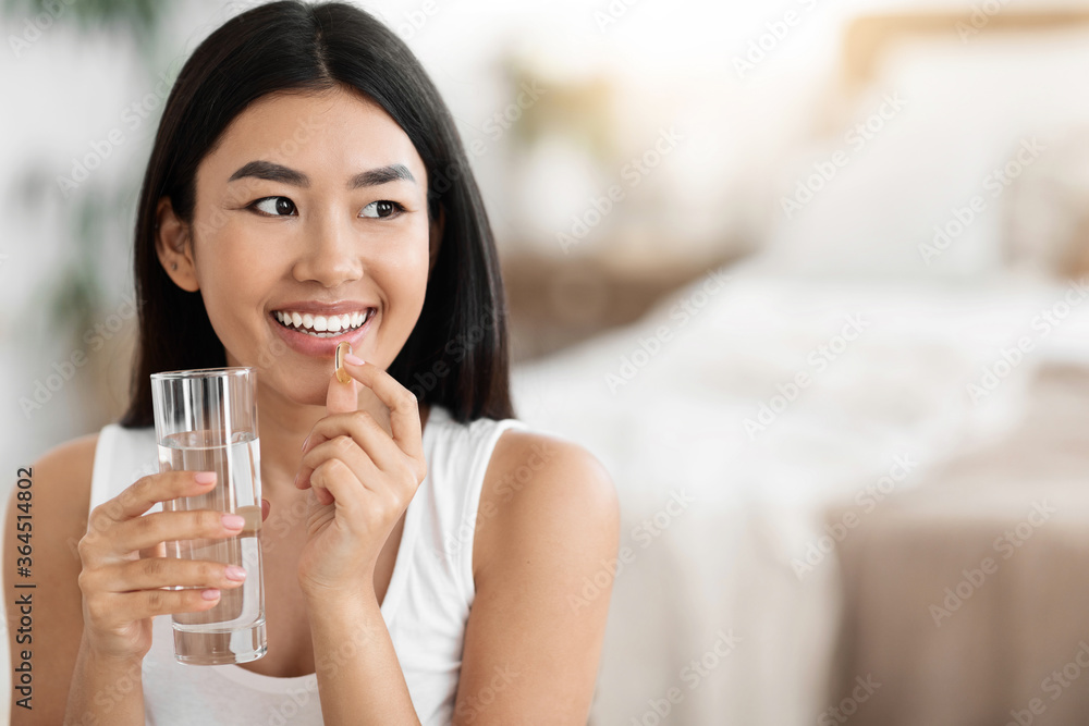 Happy Asian Woman Taking Pill And Holding Glass Of Water Happy Asian Woman Taking Pill And Holding Glass Of Water