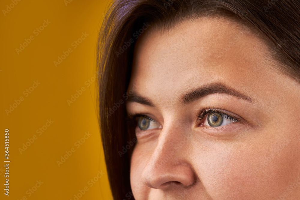 magical, clean look of a green-eyed girl. attractive brunette lady looks away, natural eye colour. yellow background magical, clean look of a green-eyed girl. attractive brunette lady looks away, natural eye colour. yellow background