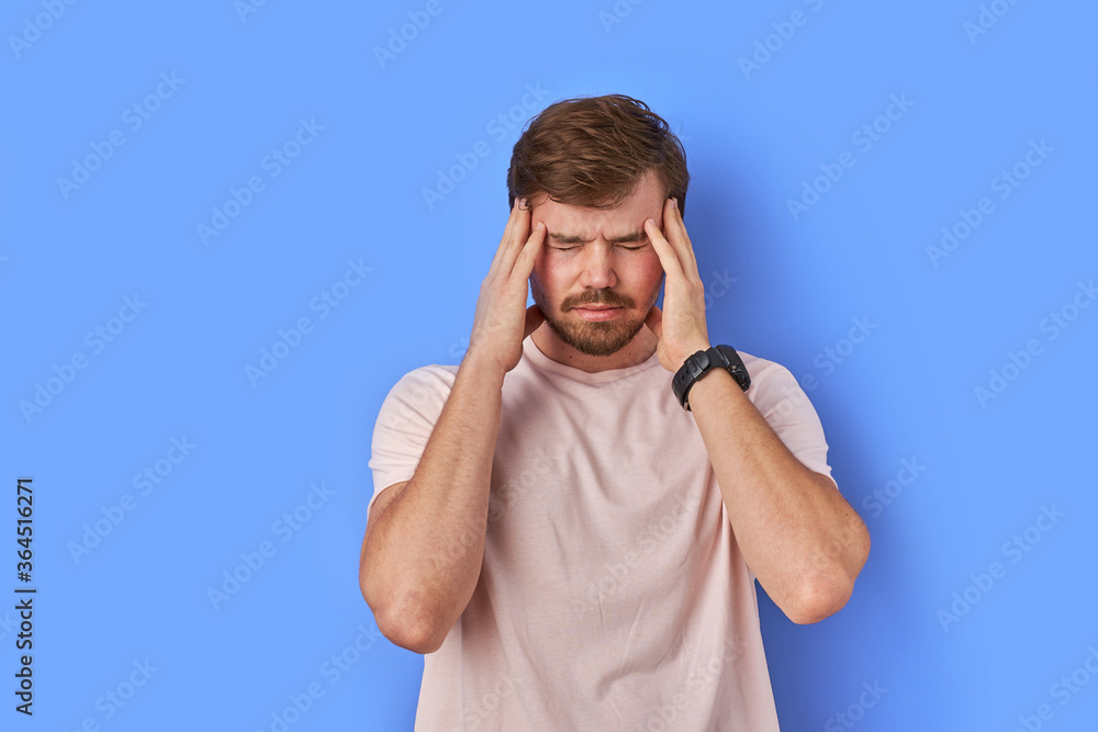 young guy has head ache, caucasian male feels unpleasant pain in the temple. isolated in studio young guy has head ache, caucasian male feels unpleasant pain in the temple. isolated in studio