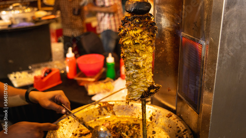 Chicken grilled in a rotating skewer at a food festival to serve Shawarma