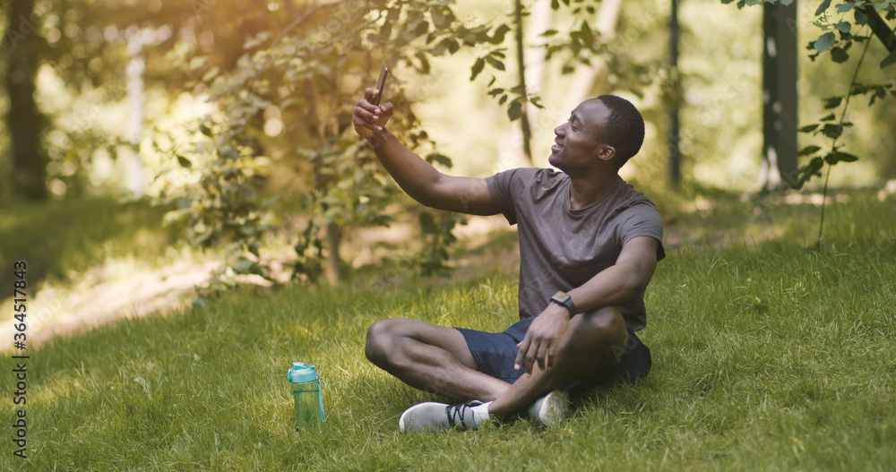 Happy african guy taking selfie on mobile phone in park Happy african guy taking selfie on mobile phone in park
