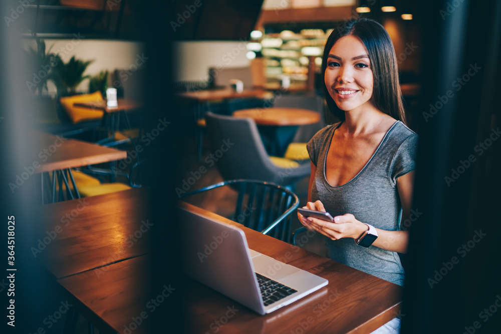 Portrait of smiling female freelancer using laptop computer for searching information about remote work, cheerful hipster girl updating software on netbook using wireless connection in coffee shop Portrait of smiling female freelancer using laptop computer for searching information about remote work, cheerful hipster girl updating software on netbook using wireless connection in coffee shop