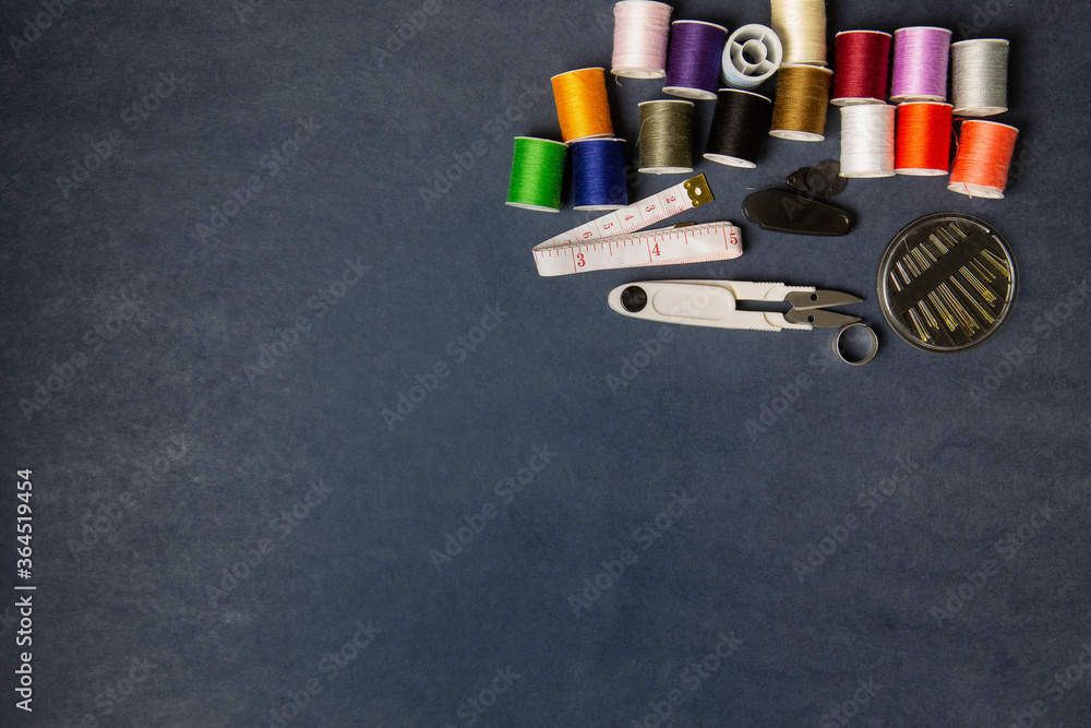 Hight view Sewing tools group and spools of thread on gray paper backdrop Hight view Sewing tools group and spools of thread on gray paper backdrop