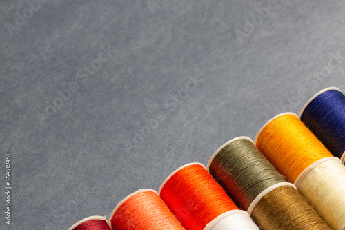 Many color row spools of thread on lower right corner on gray background photo