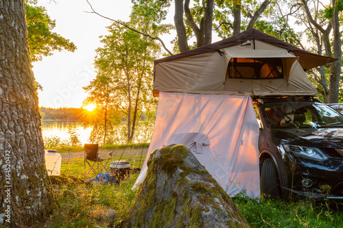 Suv with a roof top tent at sunset by a lake in Sweden