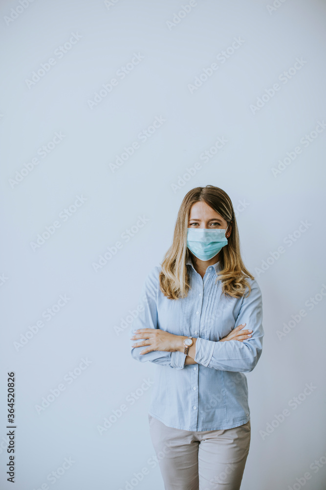 Young businesswo man with face mask stands by the wall in the office Young businesswo man with face mask stands by the wall in the office
