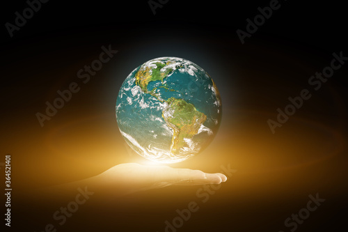 Environment concept. Earth with light in human hand on black background. Elements of this image furnished by NASA