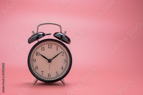 closeup of beautiful black alarm clock on pink background wit copy space.