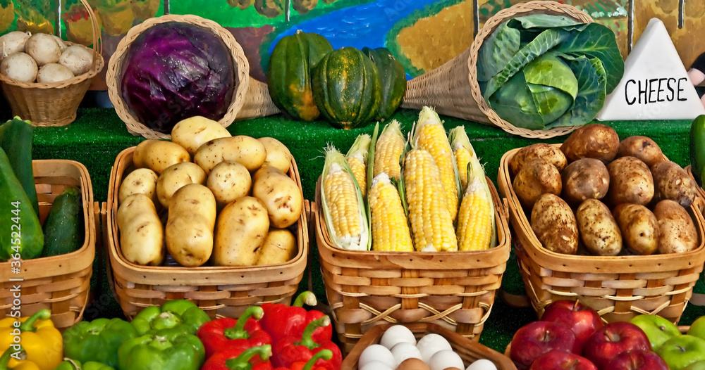 This still life is many vegetables in baskets and some fruits, for fresh, healthy produce. There are potatoes, corn on the cob, zucchini, bell peppers, apples, eggs, mushrooms, squash, and purple and This still life is many vegetables in baskets and some fruits, for fresh, healthy produce. There are potatoes, corn on the cob, zucchini, bell peppers, apples, eggs, mushrooms, squash, and purple and