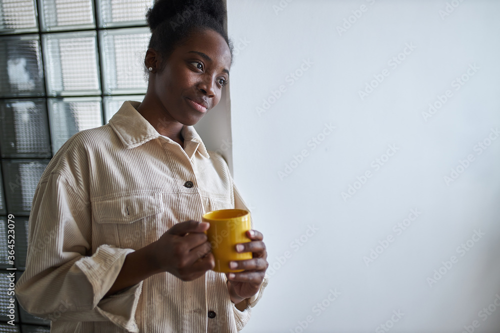 young and beautiful black african american lady drinks cup of tea at home while she has free time, woman stand enjoying. young and beautiful black african american lady drinks cup of tea at home while she has free time, woman stand enjoying.