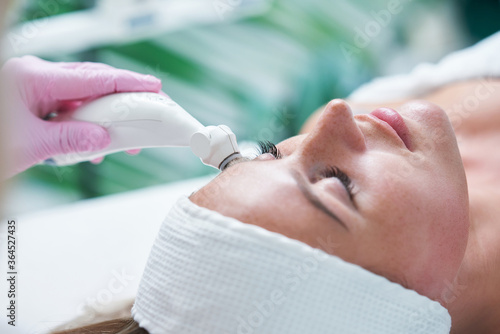 Tablou pe pânză Adult woman in beauty salon undergoing face hydrogen purification