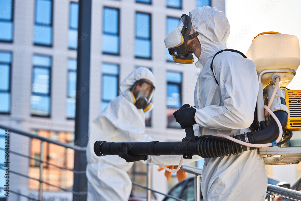 professional cleaning and disinfection at town complex amid the coronavirus epidemic. two workers prevent and control epidemic. in protective suit and mask