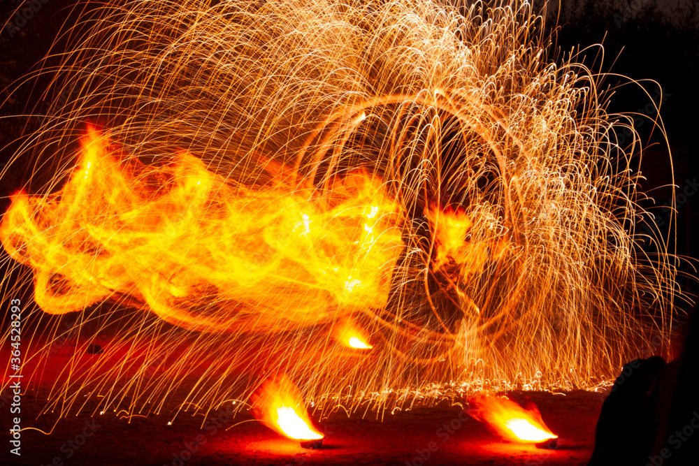 A big fountain of sparks flying off and a huge flame during a fire show