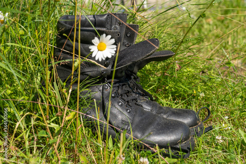 Old leather Hiking boots in the green grass. Summer is a time of travel. Close up.