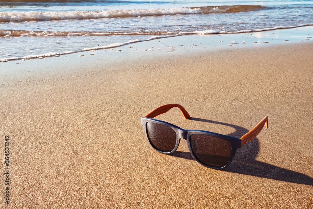 Blue sunglasses lay on the beach
