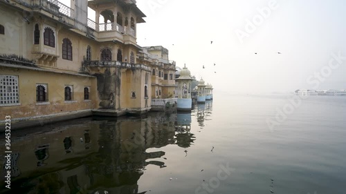 Flock Of Birds Flying Over The Lake Pichola Near The Ambrai Ghat In Udaipur, Rajasthan, India During Sunrise.  - wide shot photo