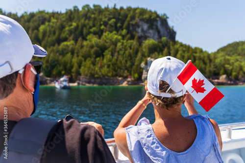 View of a man and woman with the Canadian flag on a boat in Ontario, Bruce Peninsula