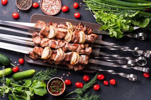 Fresh, home-cooked on the grill fire meat beef shish kebab with vegetables and spices, with barbecue sauce and ketchup, on a dark background. Shish kebabs - grilled meat and vegetables Lamb Skewers