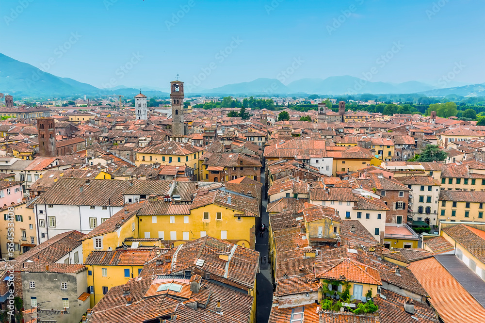 A narrow street dissects the rooftop view of Lucca, Italy in summer