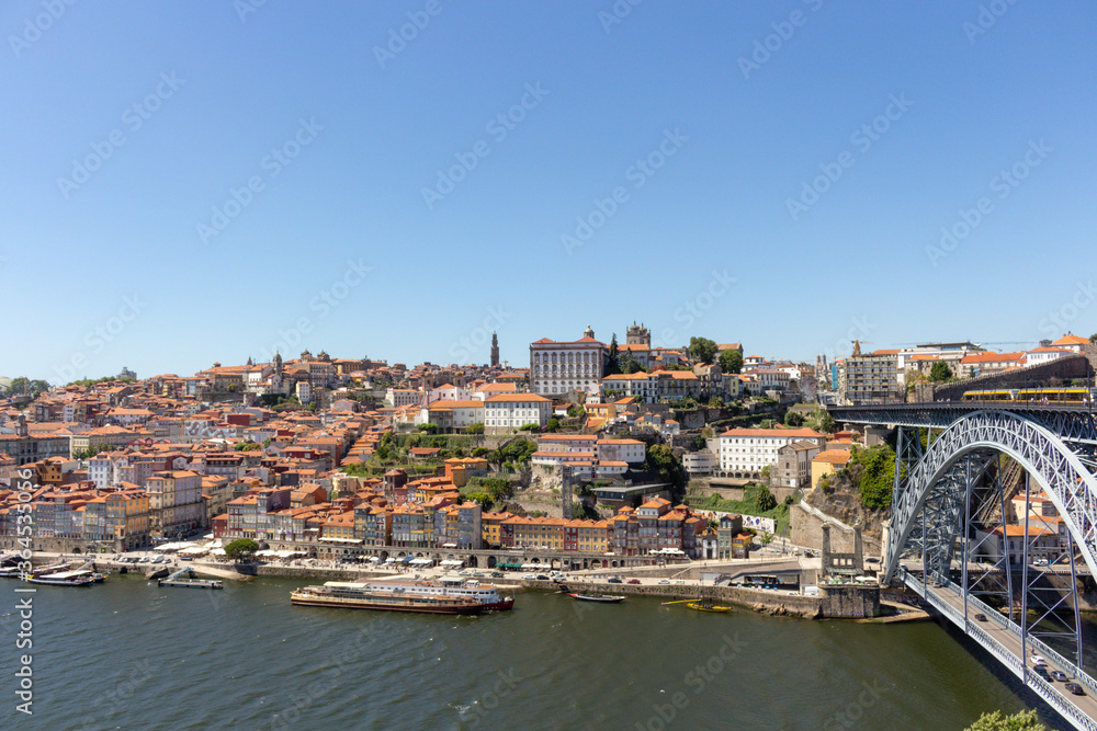 The Dom Luis I Bridge over the Douro River and the colorful houses of Porto Ribeira, traditional facades, old multi-colored houses with red roof tiles on the embankment in the city of Porto, Portugal.