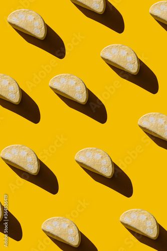Pattern of tasty marshmallows with hard shadows on a yellow background.