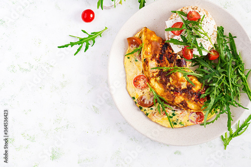 Omelette with tomatoes, cheese and green herbs on plate. Frittata - italian omelet. Top view, overhead, copy space